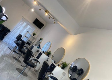 Chic interior of Innovative Salon | Hair & Beauty in London, England, GB featuring modern chairs and mirrors.