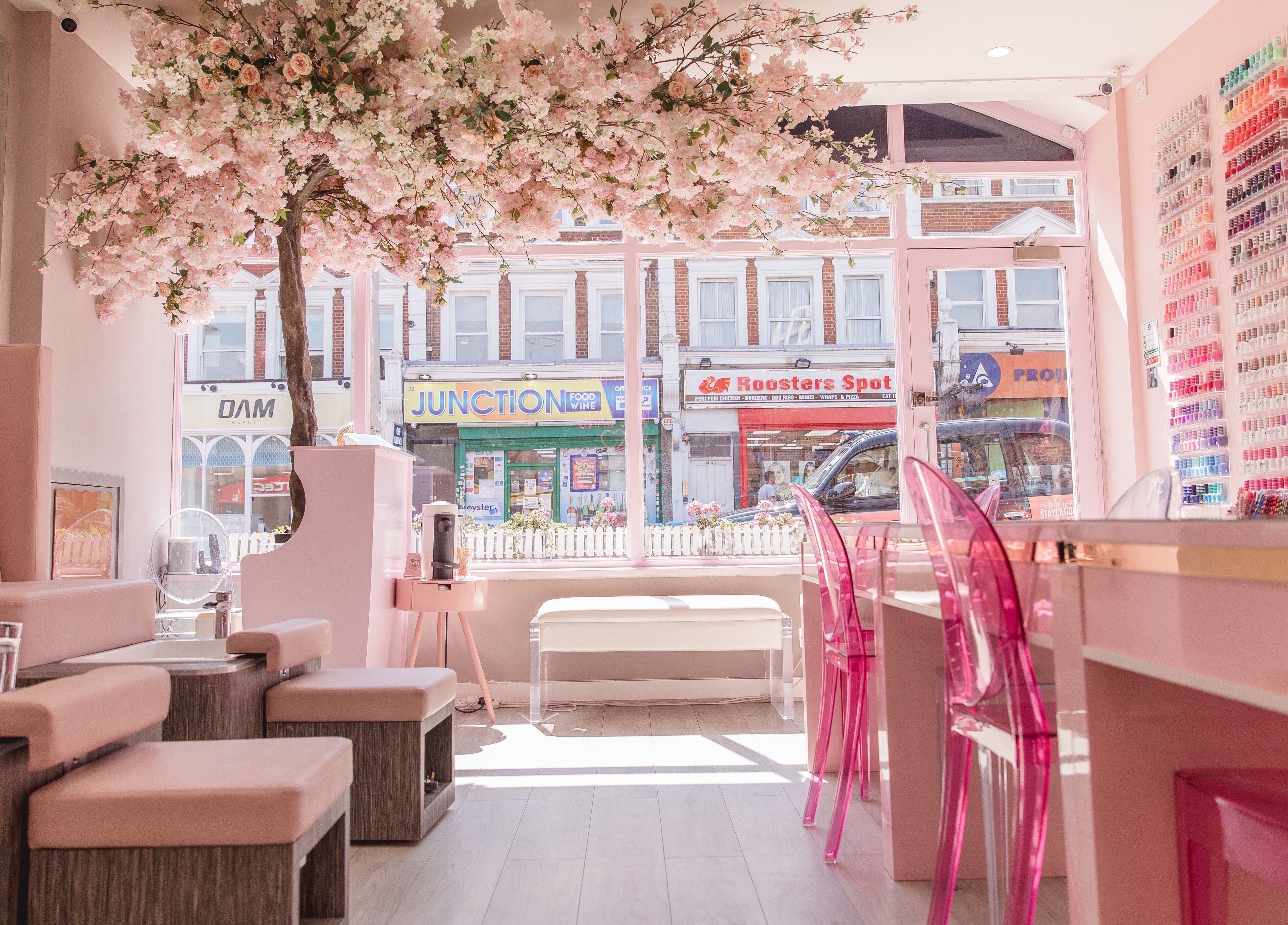Elegant interior of Nail'd It Clapham salon in London, England, GB, featuring chic pink decor and nail polish display.