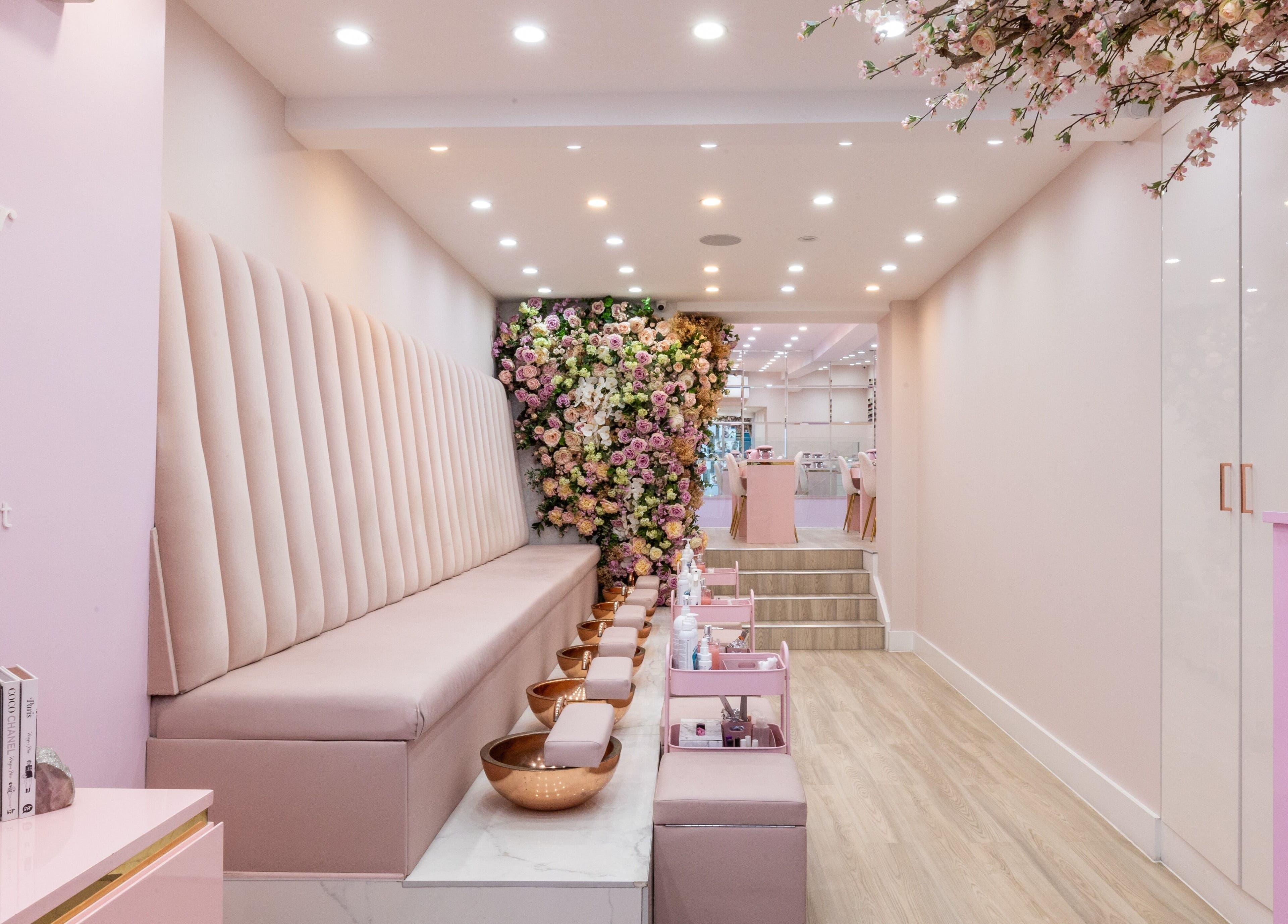 Luxurious interior of Nail'd It Marylebone, London, England, GB. Elegant seating with floral decor and soft lighting.