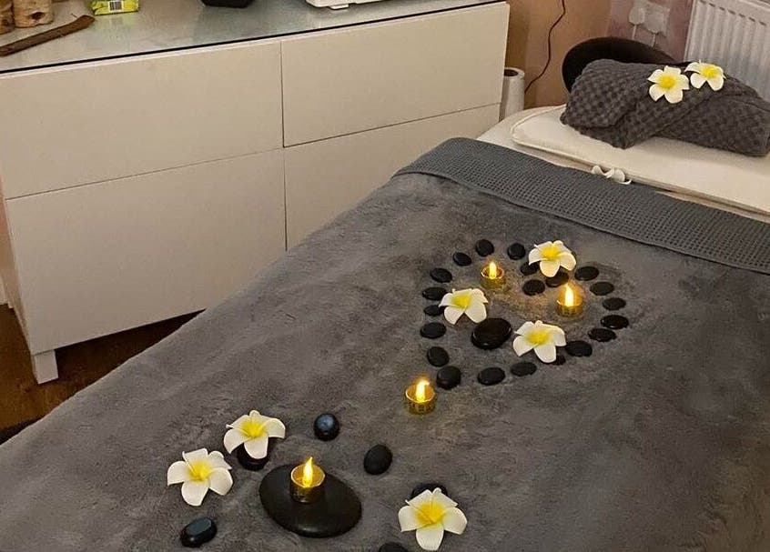 Serene spa setup at Elegance Beauty in Osmaston, England, GB with stones and flowers on a massage bed.