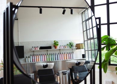 Modern salon interior at Studio 90 in London, England, GB, featuring sleek chairs and lush greenery.
