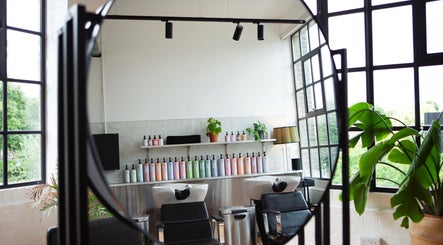 Modern salon interior at Studio 90 in London, England, GB, featuring sleek chairs and lush greenery.