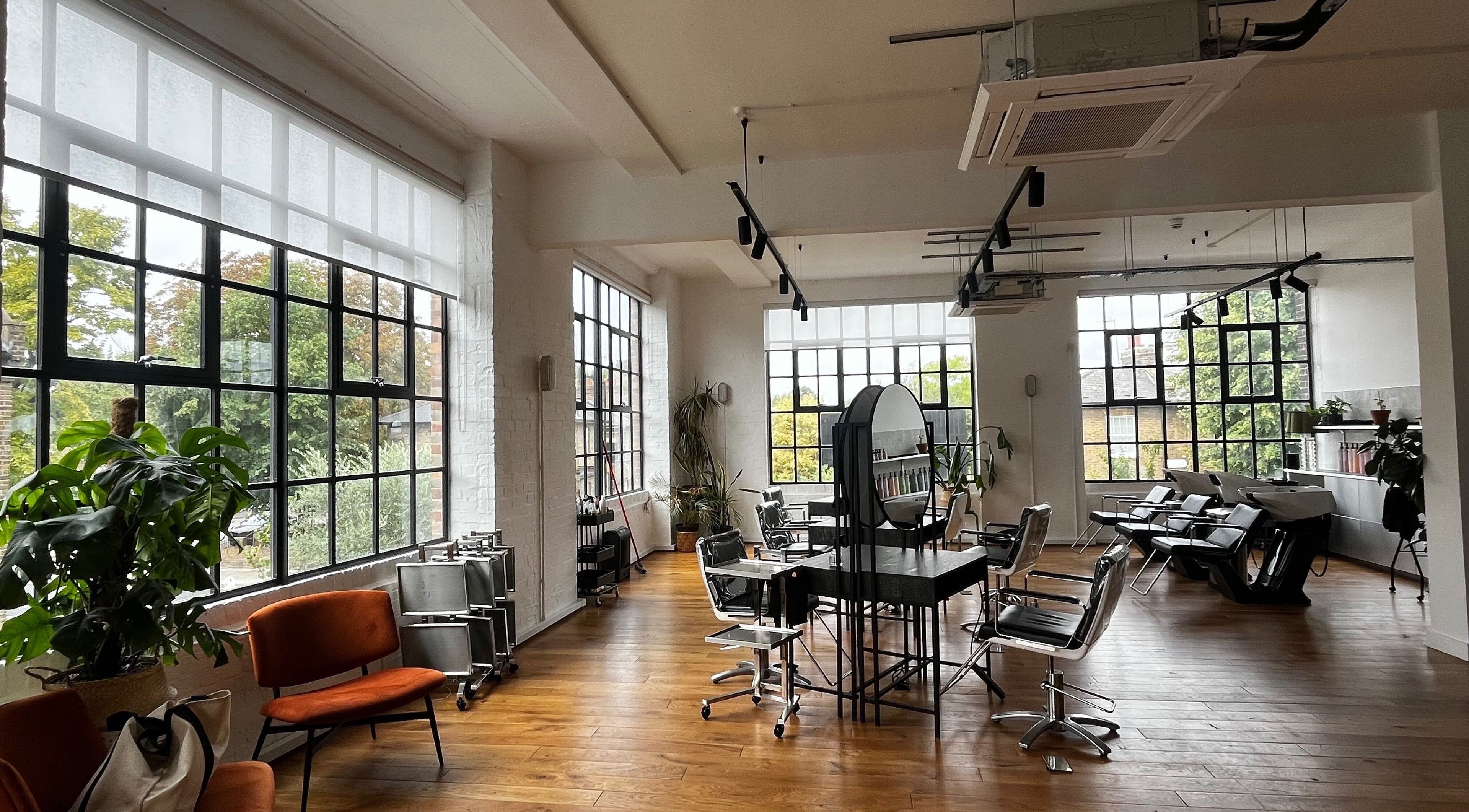 Bright and modern interior of Studio 90 in London, England, GB, featuring large windows and stylish salon chairs.