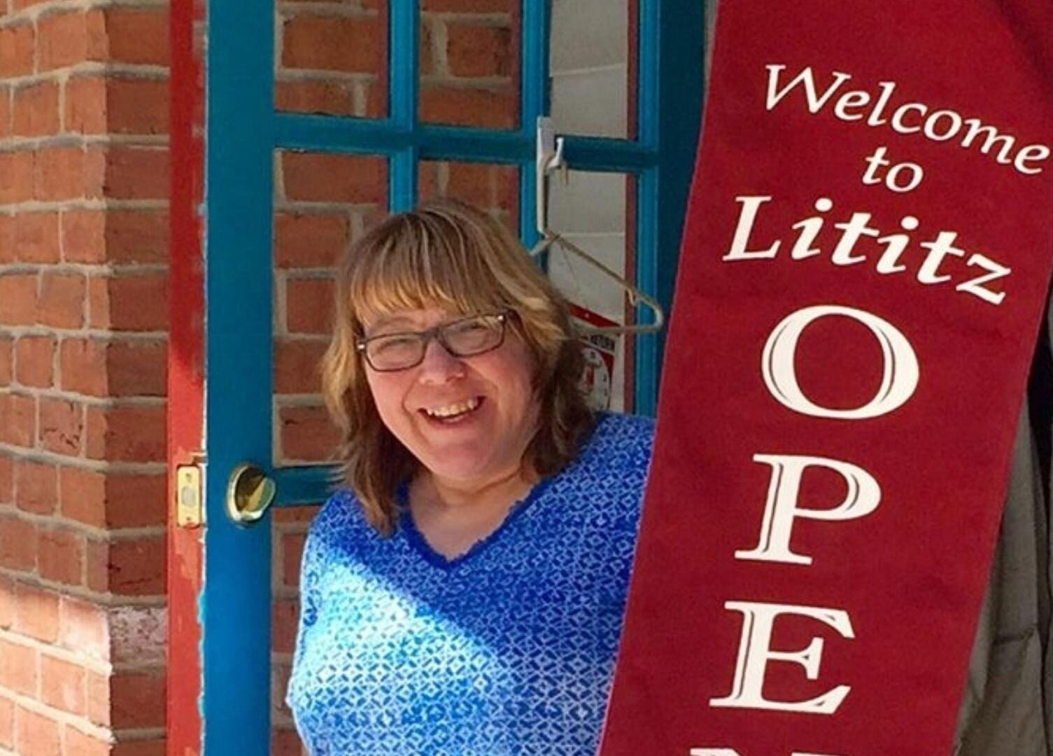 Woman smiling at the entrance of apPIERances Salon & Barbering, Lititz, Pennsylvania, US.