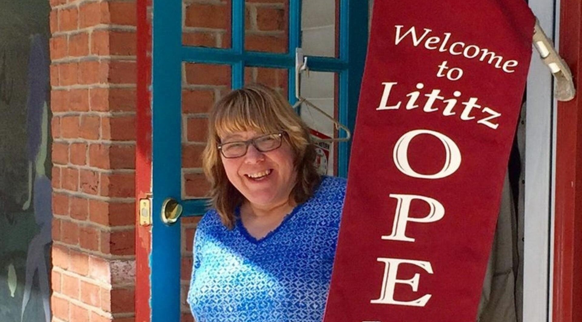 Woman smiling at the entrance of apPIERances Salon & Barbering, Lititz, Pennsylvania, US.