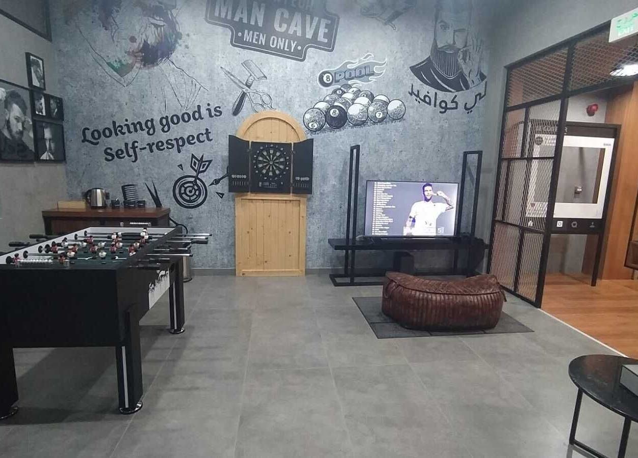 Modern men's recreation area at Le Coiffeur Salon Dar-Al-Salam, الدوحة, الريان, QA with games and seating.
