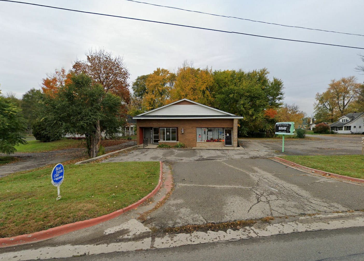 Front view of Aaries Styles Salon in Ypsilanti, Michigan, US, surrounded by lush greenery and autumn trees.