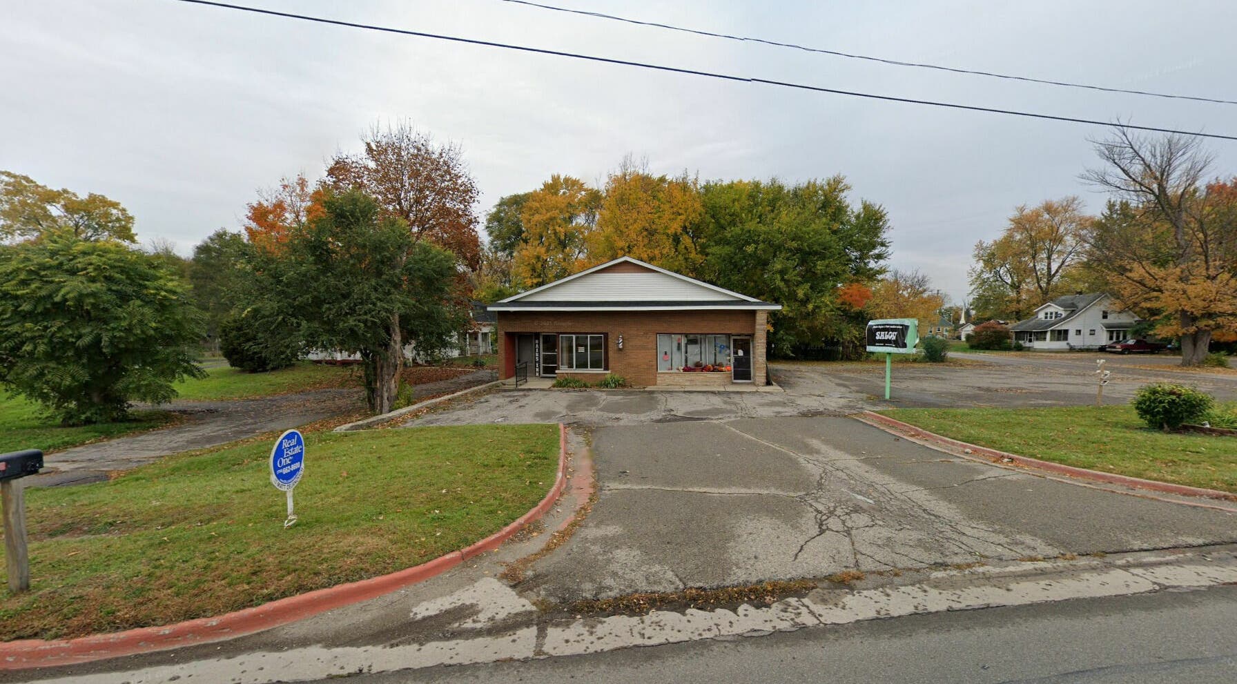 Front view of Aaries Styles Salon in Ypsilanti, Michigan, US, surrounded by lush greenery and autumn trees.