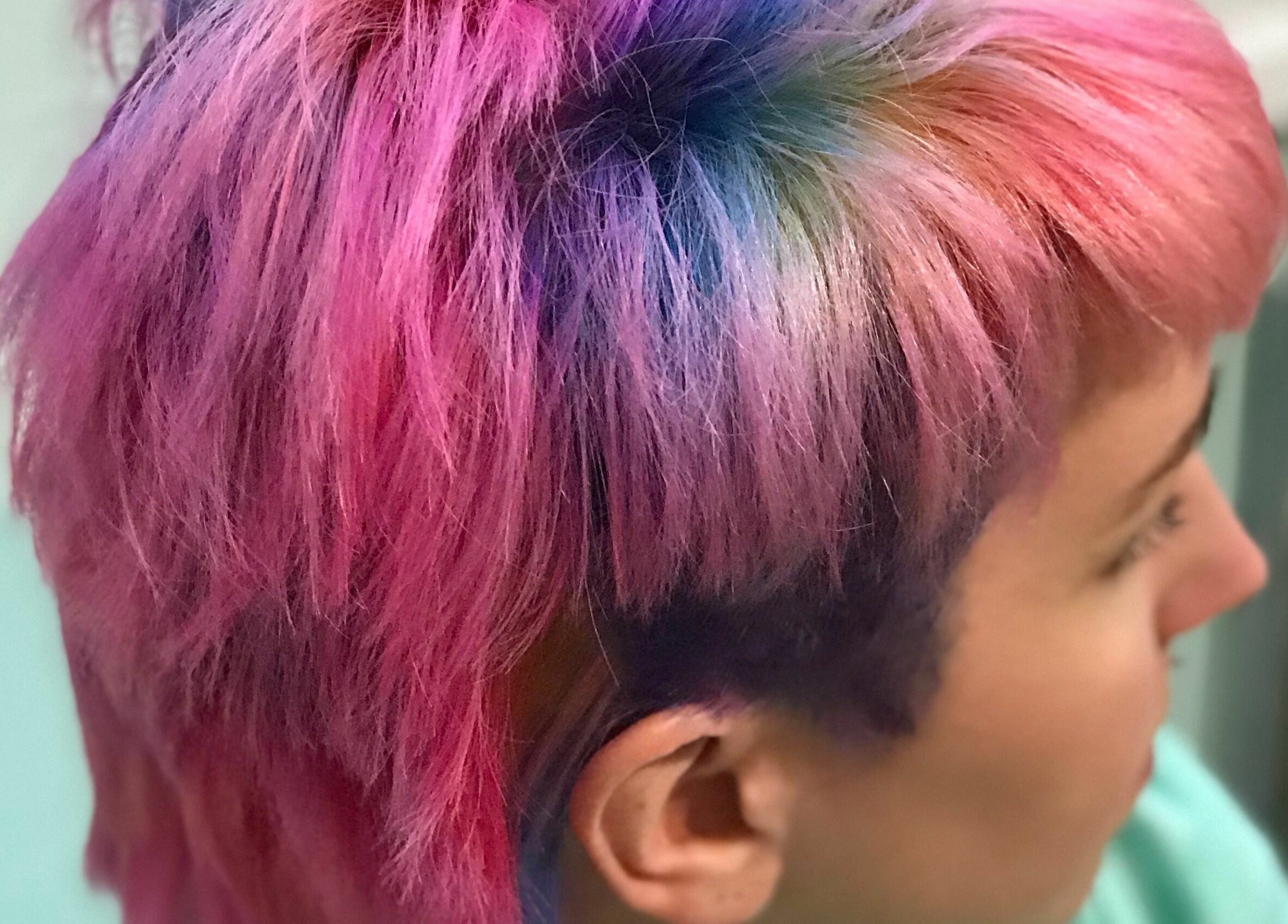 Colorful short hairstyle at Aaries Styles Salon in Ypsilanti, Michigan, US showcasing vibrant pink tones.