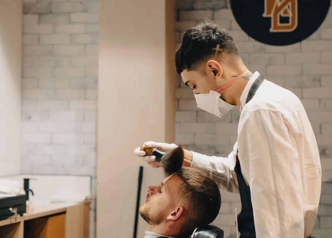 Barber at Kirkwoods Barbers Stoneridge in Auckland, NZ, expertly styling a client's hair.
