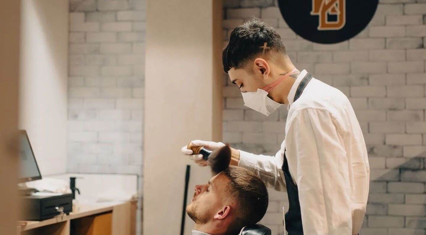 Barber at Kirkwoods Barbers Stoneridge in Auckland, NZ, expertly styling a client's hair.