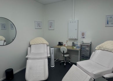 Relaxing treatment room at Glisten Haus, Auckland, Auckland, NZ featuring plush chairs and a stylish mirror.