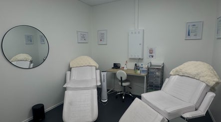 Relaxing treatment room at Glisten Haus, Auckland, Auckland, NZ featuring plush chairs and a stylish mirror.