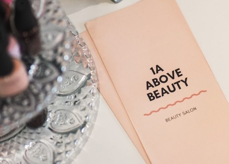 Invitation card for 1a Above Beauty, a beauty salon in Willerby, England, GB, surrounded by nail polish bottles.