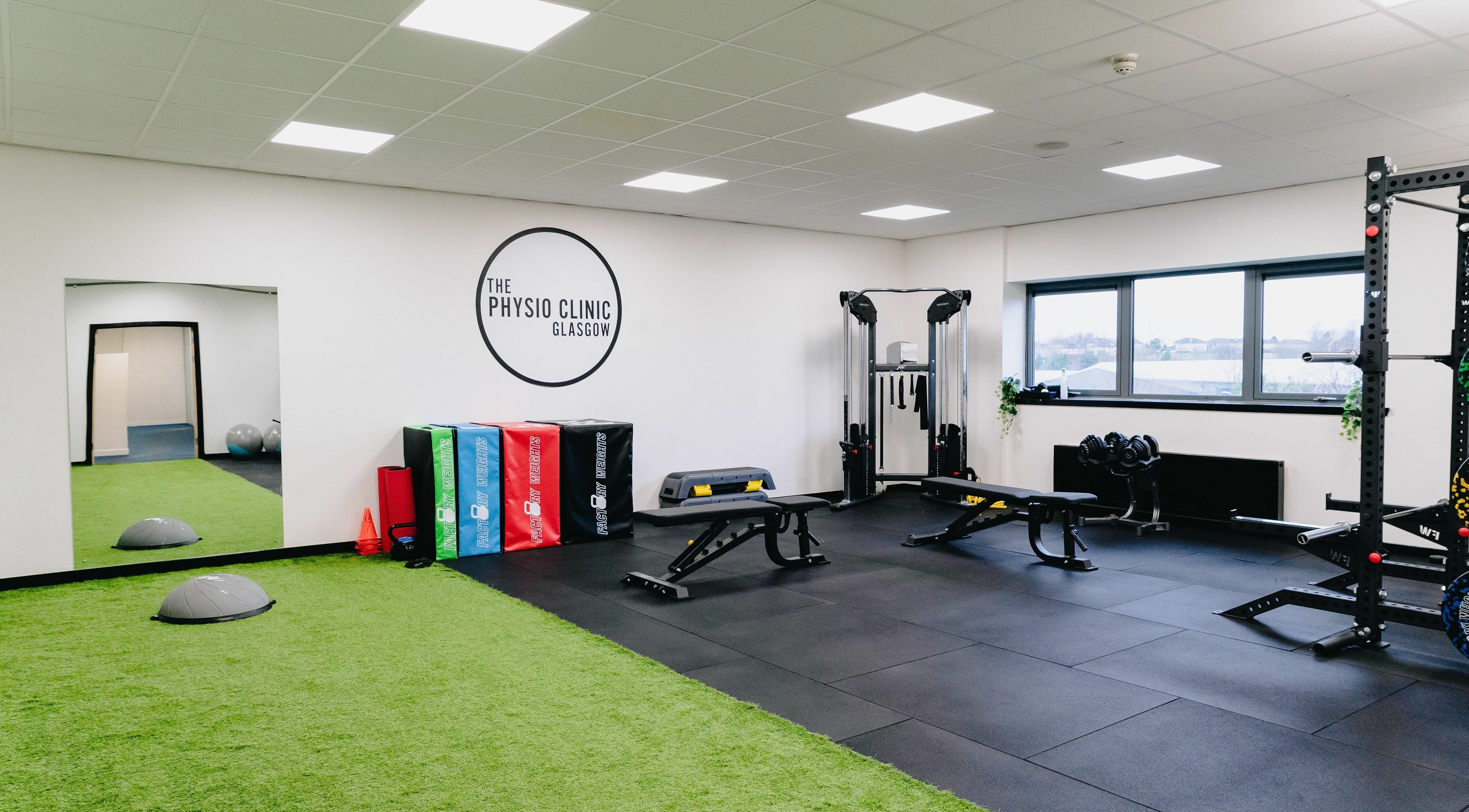 Modern gym interior at The Physio Clinic Glasgow in Glasgow, Scotland, GB with equipment and green flooring.
