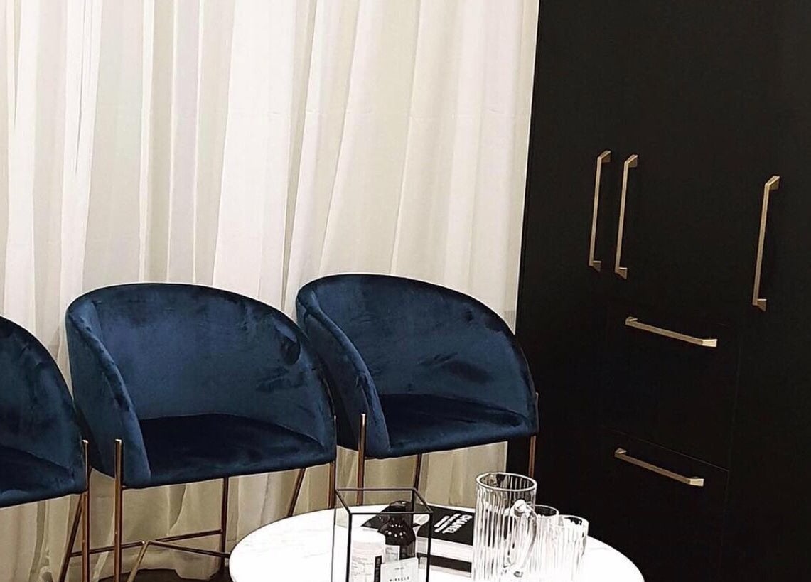 Chic seating area at Modern Aesthetics, Woolooware, New South Wales, AU featuring plush blue chairs and a stylish table.