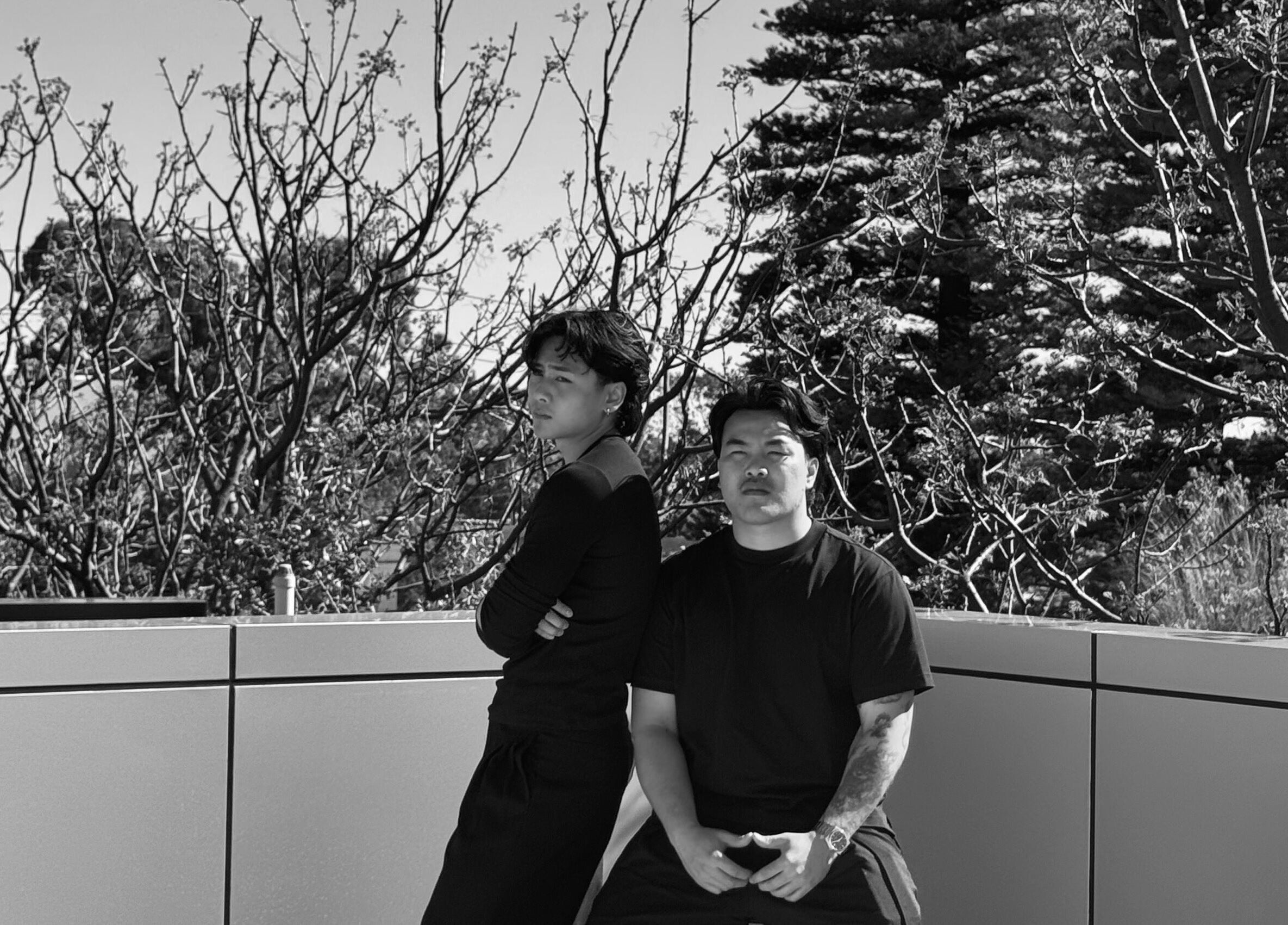 Stylish duo at NewtsTheBarber x KapitalCuts in Perth, Western Australia, AU, amid scenic trees.