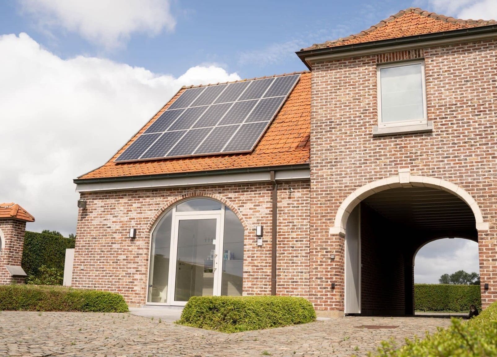 Zonnig exterieur van CuraGlow, Wevelgem, Vlaanderen, BE, met bakstenen gevel en zonnepanelen.