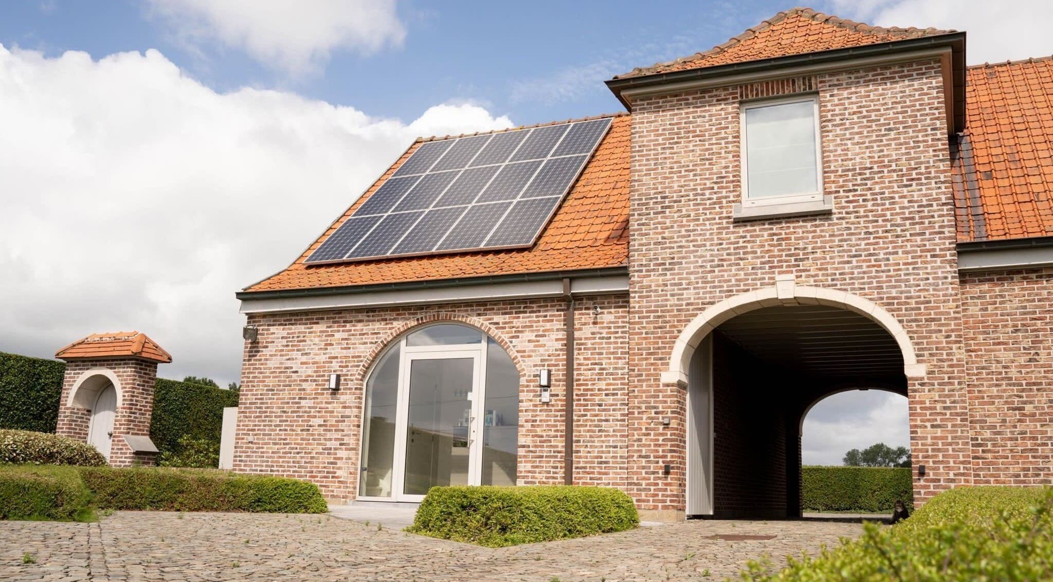 Zonnig exterieur van CuraGlow, Wevelgem, Vlaanderen, BE, met bakstenen gevel en zonnepanelen.
