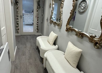 Elegant hallway at Exclusive Beauty Spa, Sutton Coldfield, England, featuring ornate mirrors and plush seating.