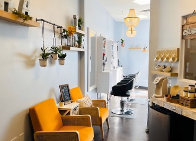 Bright, modern salon entrance at Curl & Color Studio, Las Vegas, Nevada, US with stylish chairs and hanging plants.