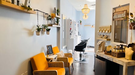 Bright, modern salon entrance at Curl & Color Studio, Las Vegas, Nevada, US with stylish chairs and hanging plants.
