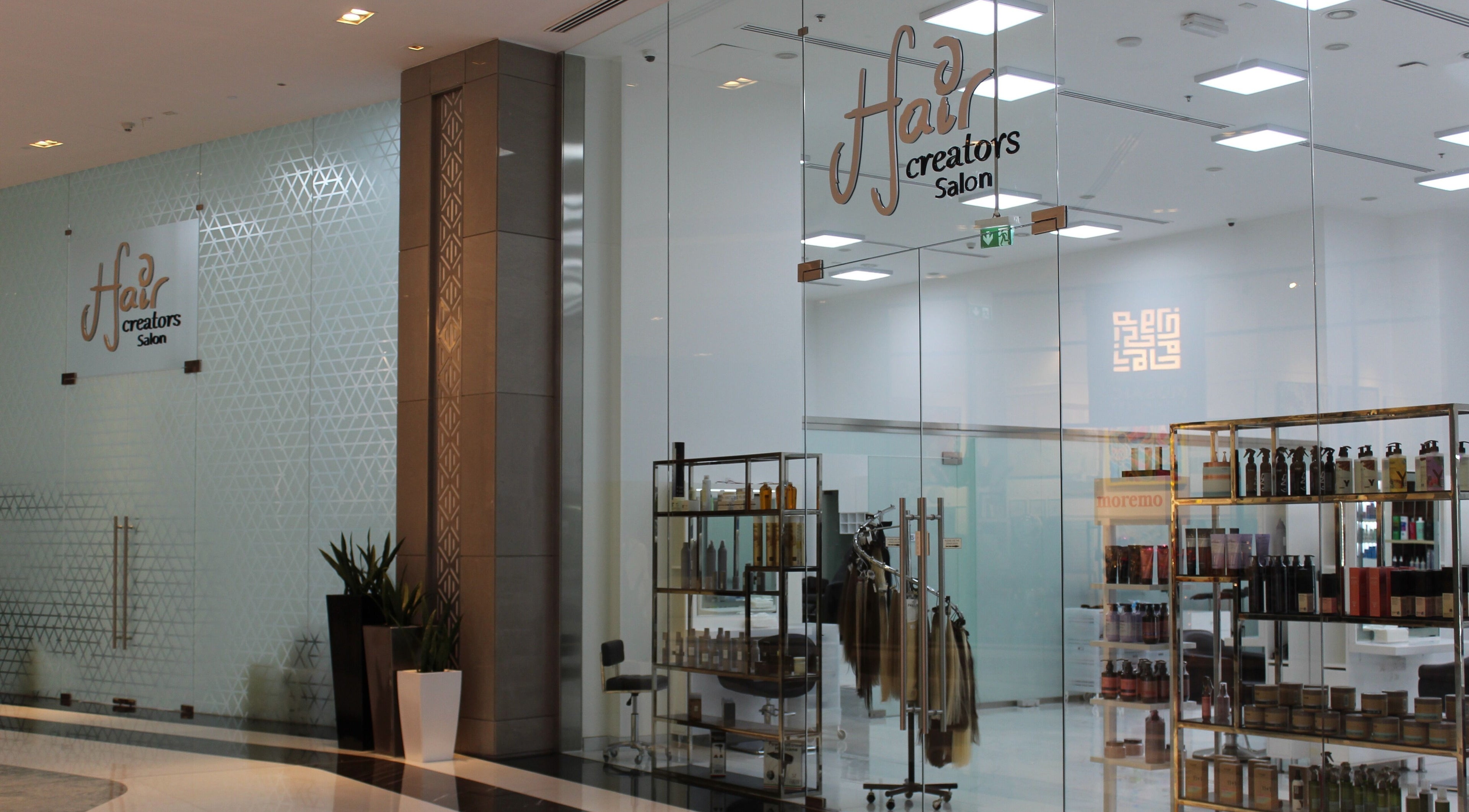 Entrance of Hair Creators Gate Avenue, Dubai, showcasing modern design with glass doors and product displays.