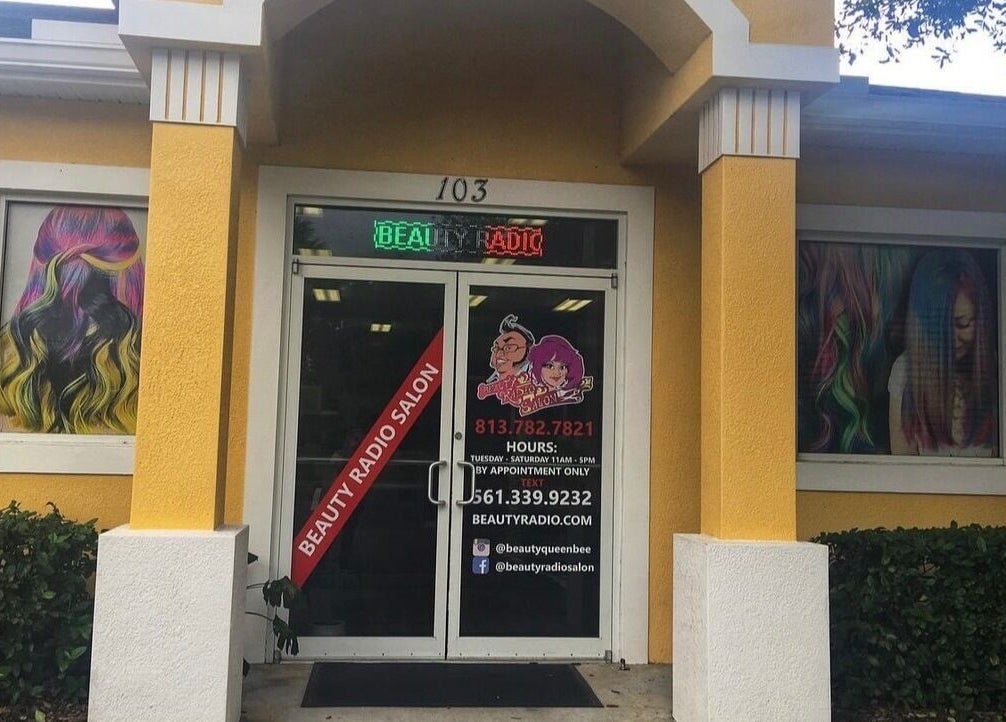 Entrance of Beauty Radio Salon in Zephyrhills, Florida, with vibrant hair mural on walls.