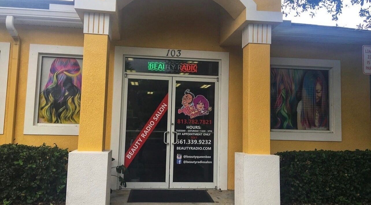 Entrance of Beauty Radio Salon in Zephyrhills, Florida, with vibrant hair mural on walls.