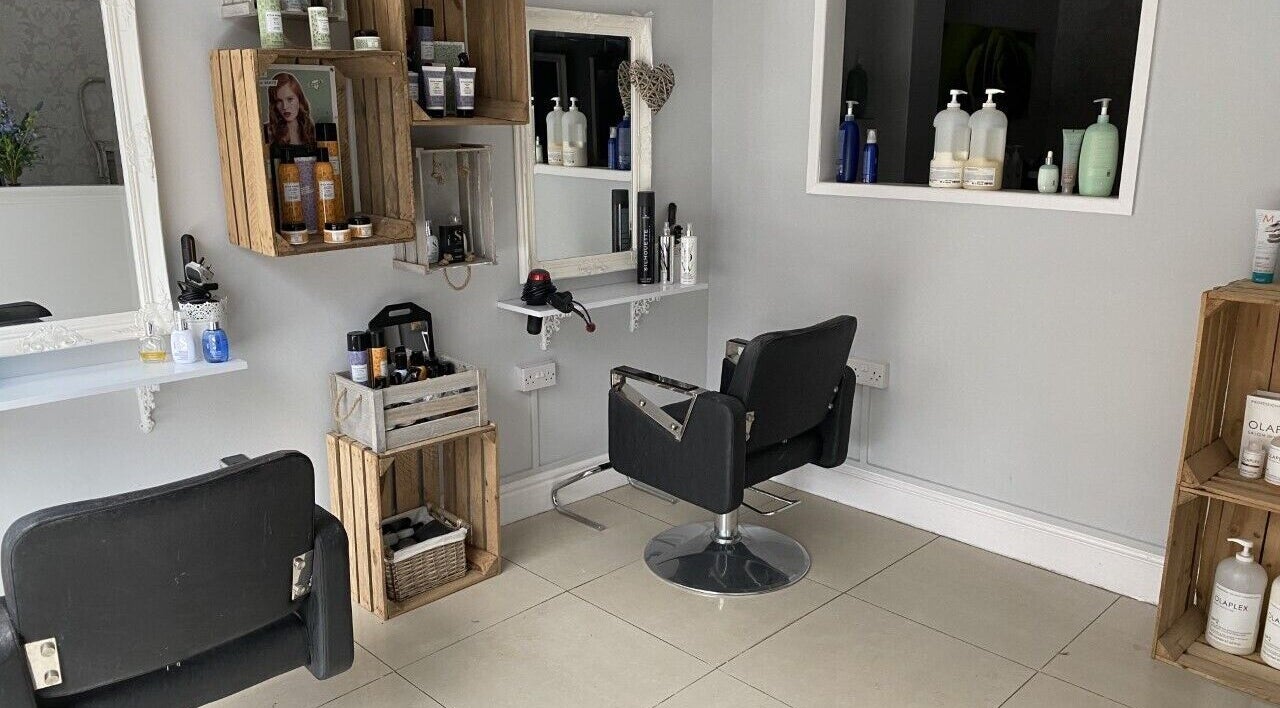 Modern salon interior at Eden Hair and Beauty, Burton-on-Trent, England, GB showcasing stylish chairs and wooden shelves.