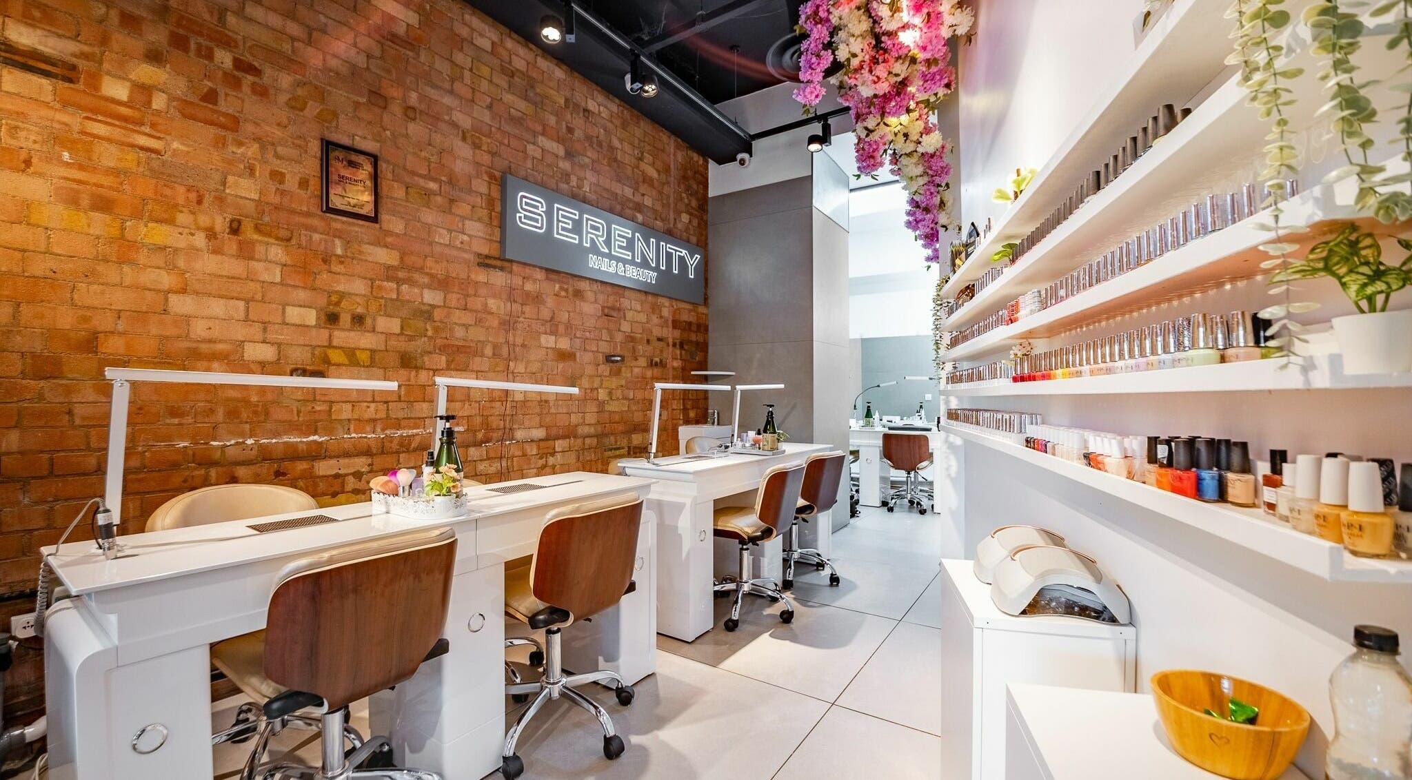 Elegant beauty salon interior at Serenity Chelsea, London, England, GB with nail stations and floral decor.
