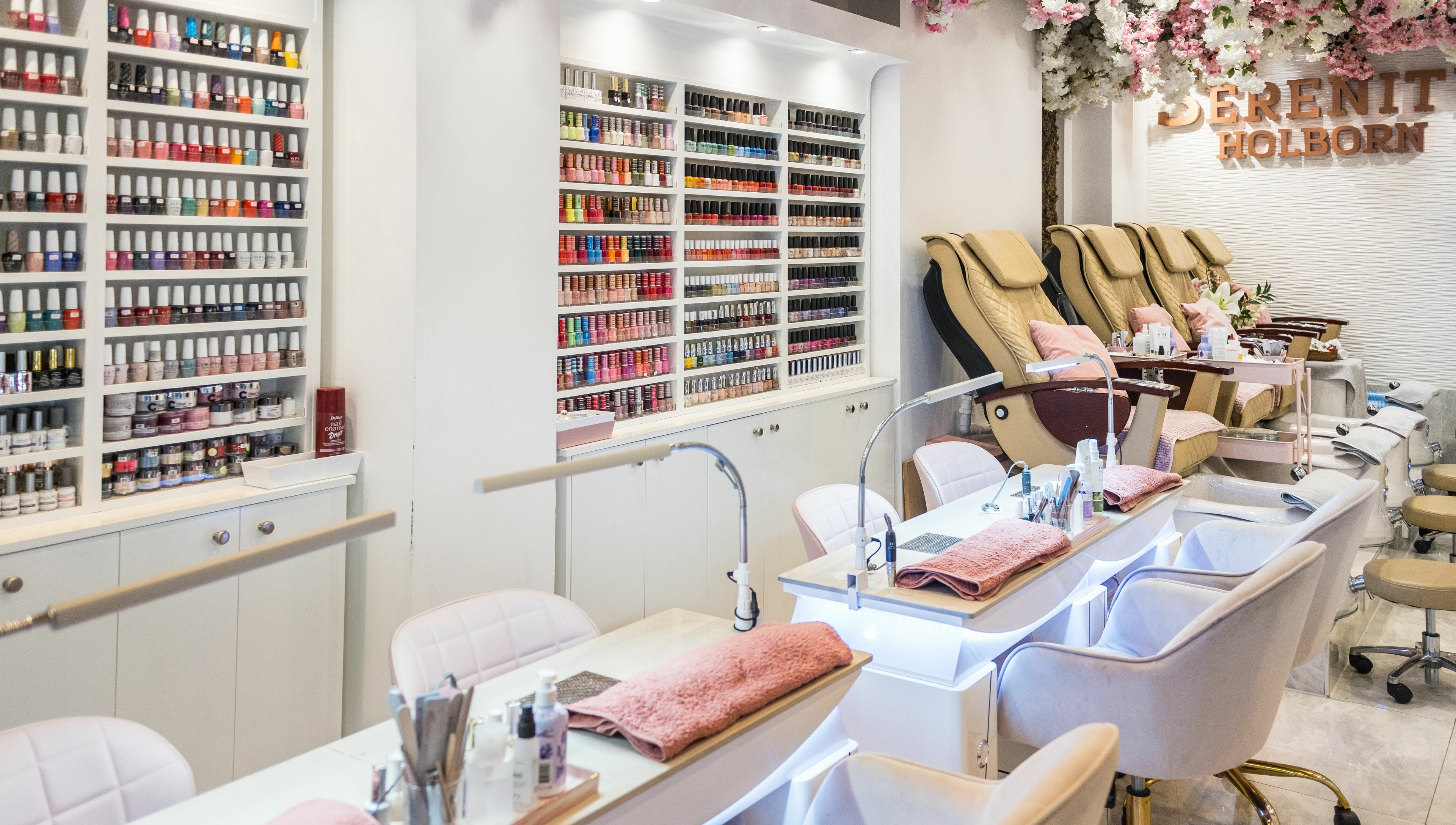 Nail salon interior at Serenity Holborn, London, England, GB, showcasing manicure stations and polishes.