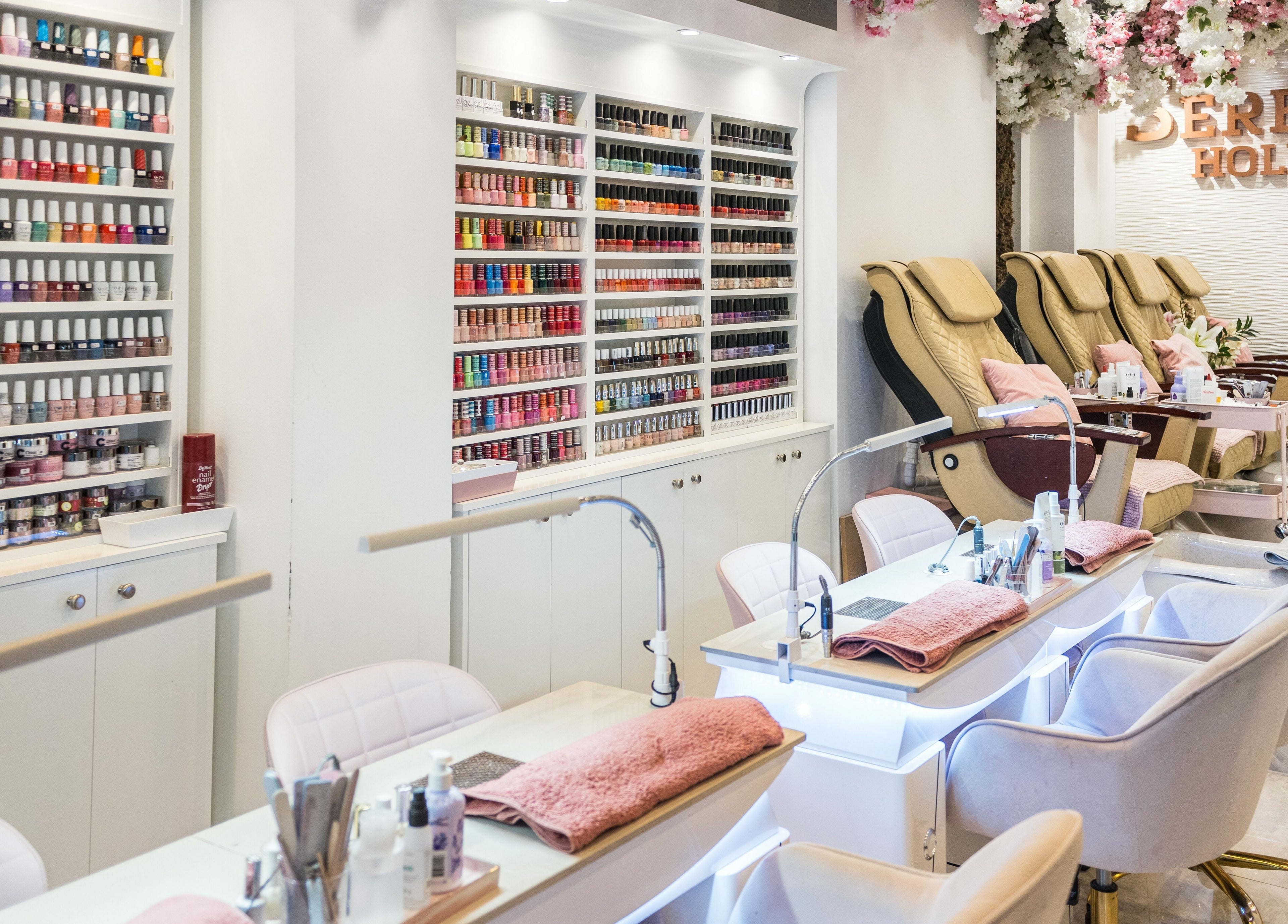 Nail salon interior at Serenity Holborn, London, England, GB, showcasing manicure stations and polishes.