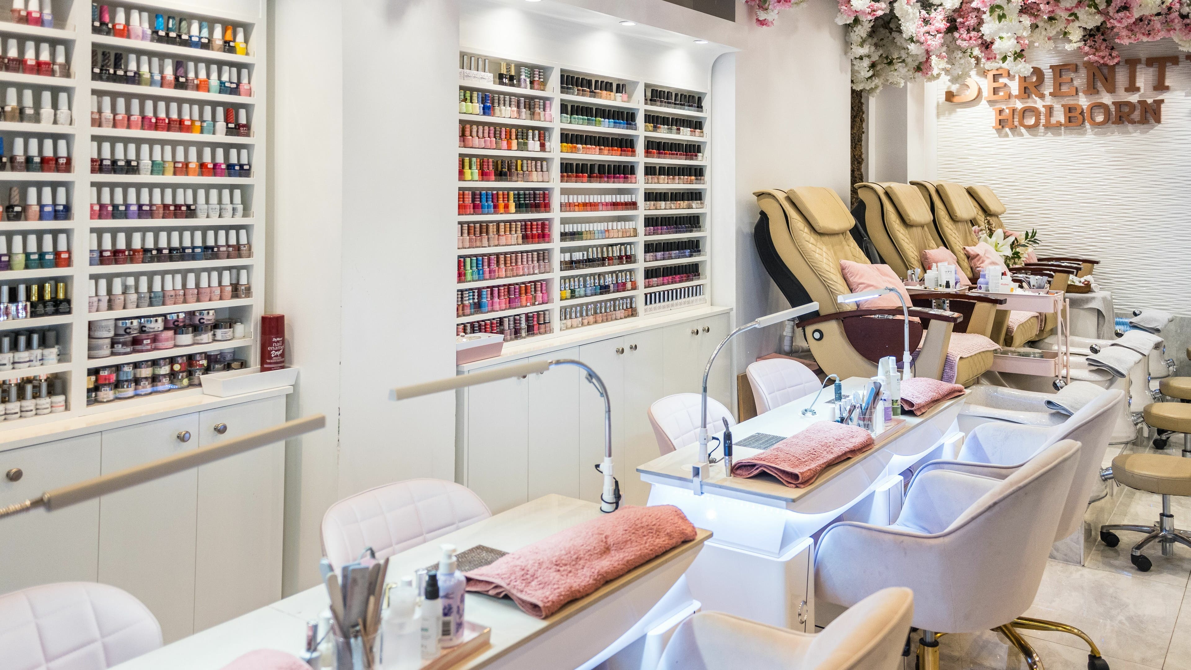 Nail salon interior at Serenity Holborn, London, England, GB, showcasing manicure stations and polishes.