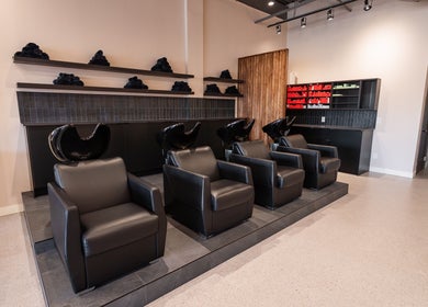 Luxurious salon wash area at In The Cut Salon, Montréal, Québec, CA with sleek black chairs and shelving.
