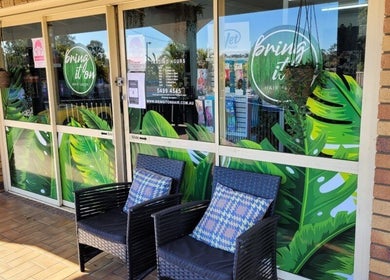 Front entrance of Bring It On Hair in Bellmere, Queensland, AU with tropical decor and seating.