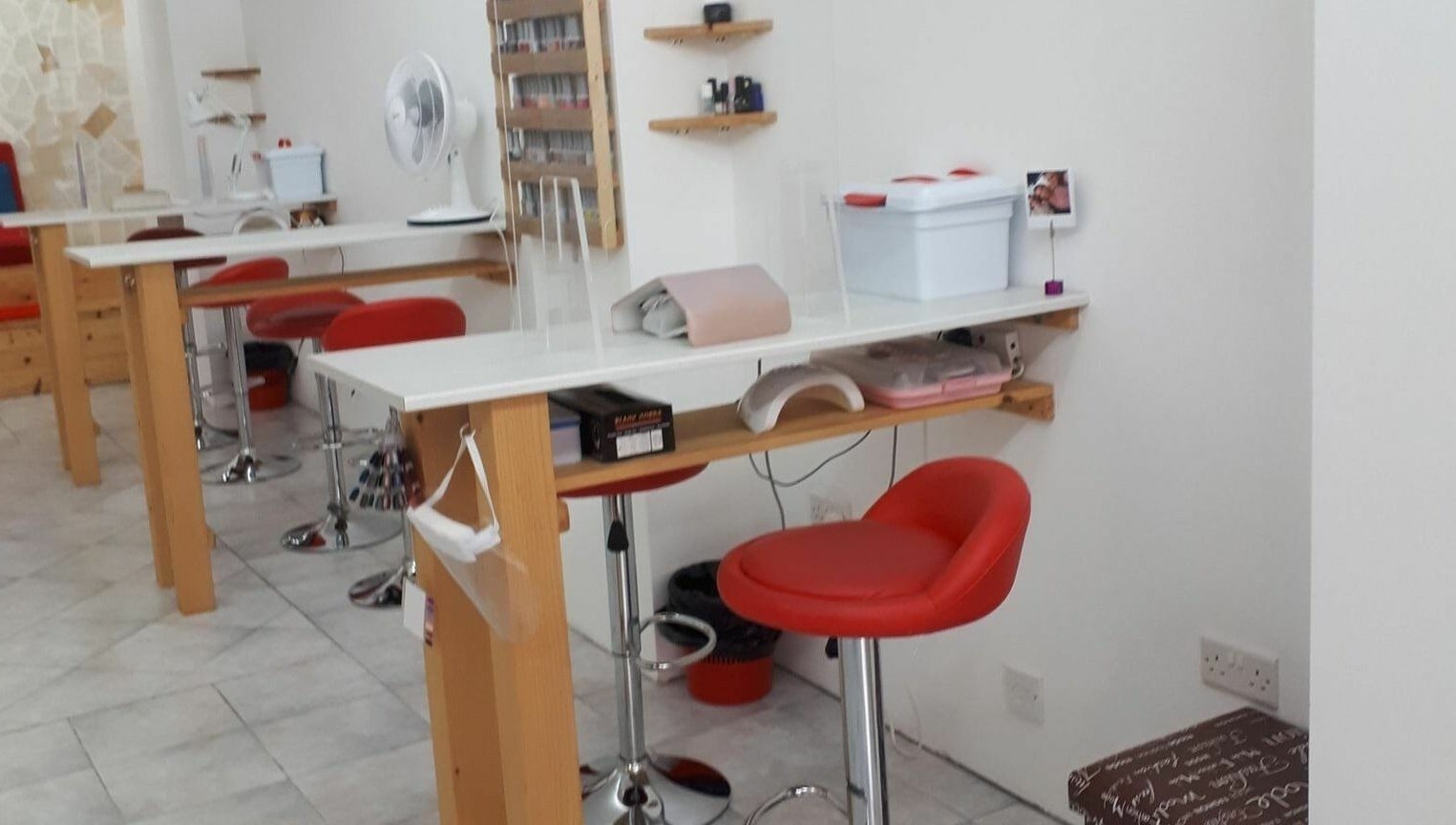 Elegant nail station at Lucie's Nails and Beauty in Tas-Sliema, MT, featuring vibrant red chairs and modern decor.