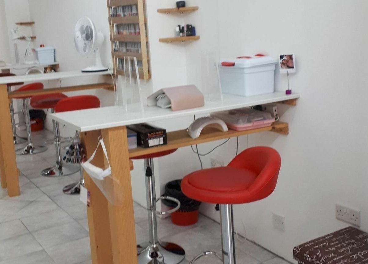 Elegant nail station at Lucie's Nails and Beauty in Tas-Sliema, MT, featuring vibrant red chairs and modern decor.
