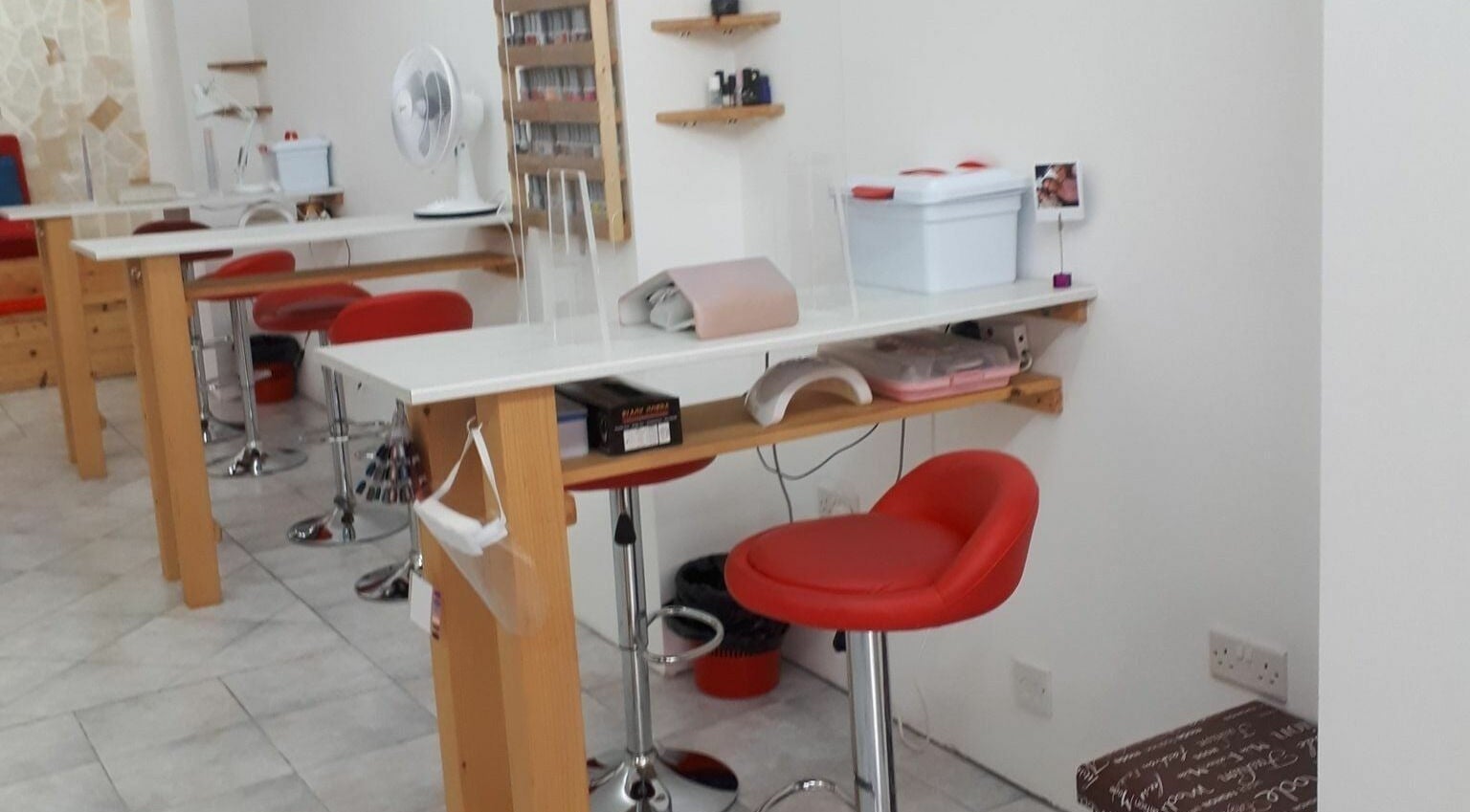 Elegant nail station at Lucie's Nails and Beauty in Tas-Sliema, MT, featuring vibrant red chairs and modern decor.