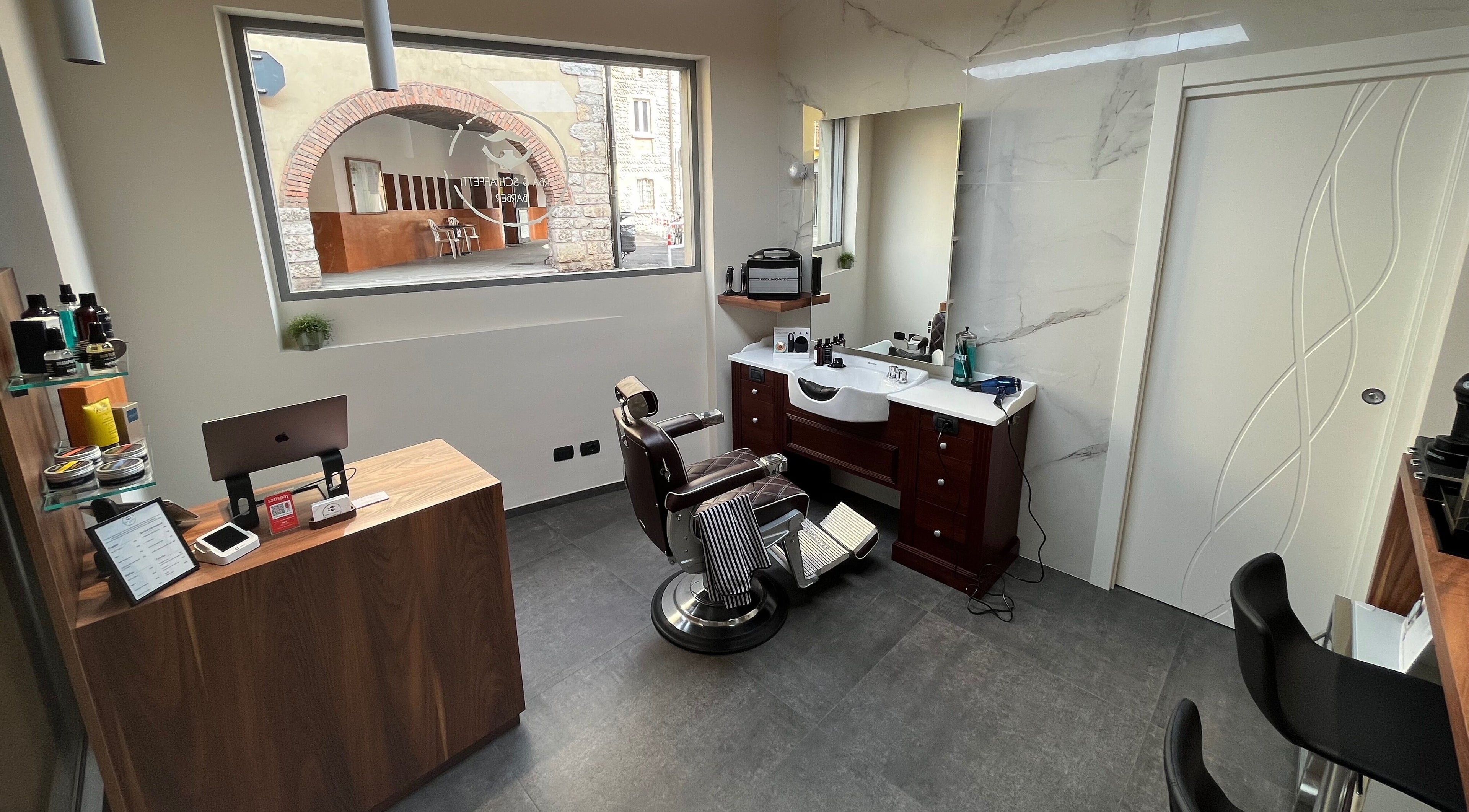 Interno elegante di Barba & Schiaffetti a Nembro, Lombardia, IT con sedia da barbiere e arredi moderni.