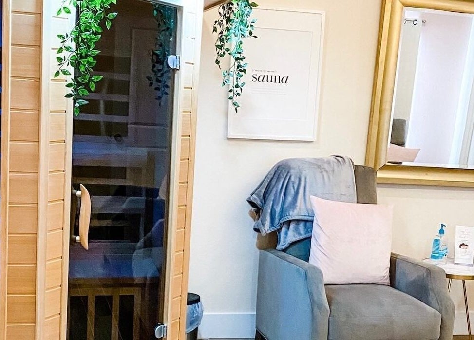 Relaxing sauna room at Energe Spa, Cypress, Texas, US, featuring a cozy chair and lush greenery.