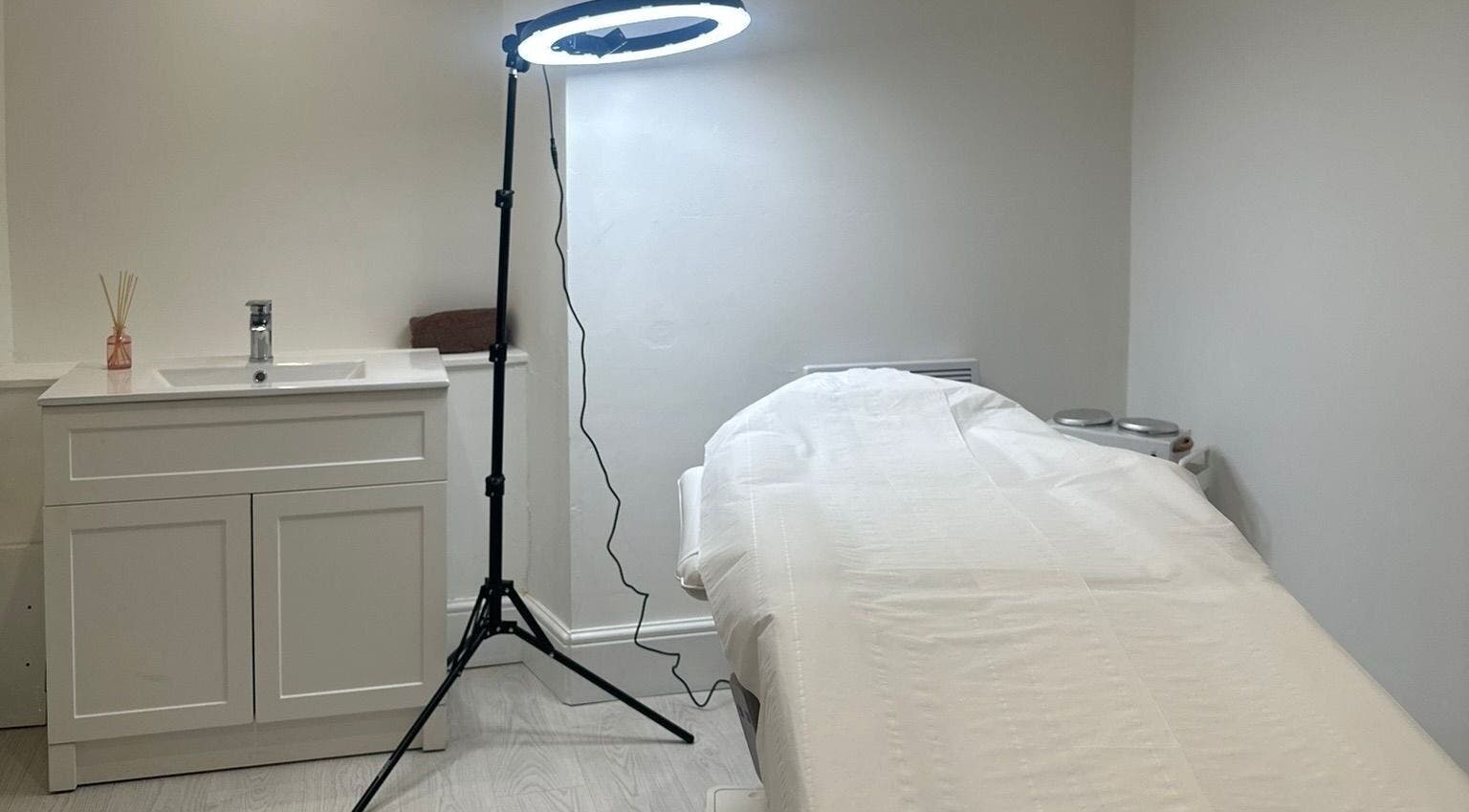 Relaxing treatment room at Rachael Louise & Co, Glasgow, Scotland, GB featuring bed, sink, and lighting.