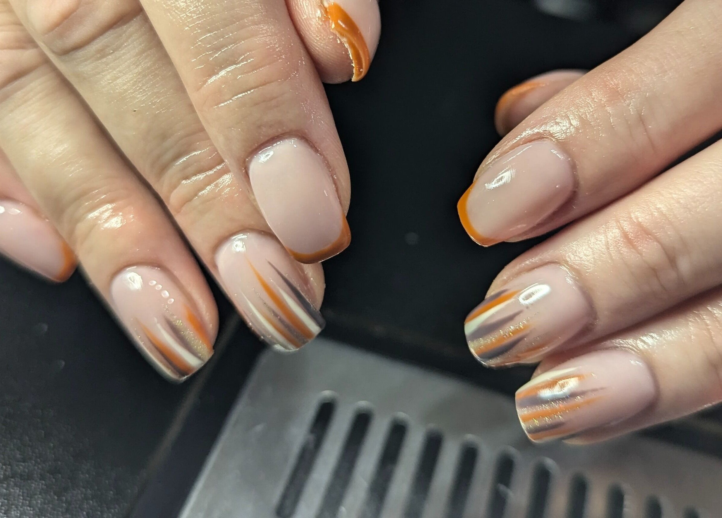 Elegant nail art showcasing orange and nude designs at Kathsklaws in Wolverhampton, England, GB.