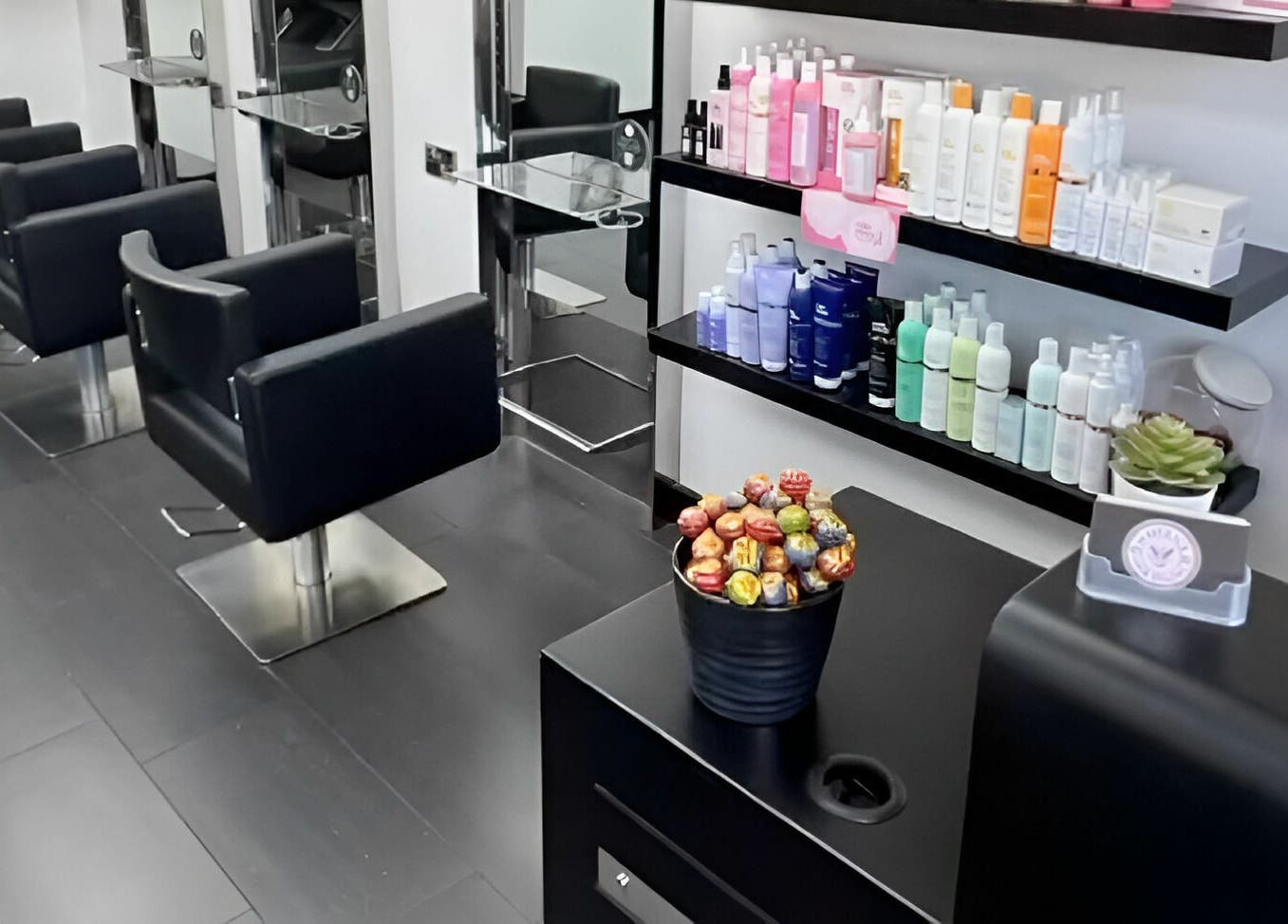 Stylish black chairs and shelves of products at Maverick Hair Studio, Angmering, England, GB.