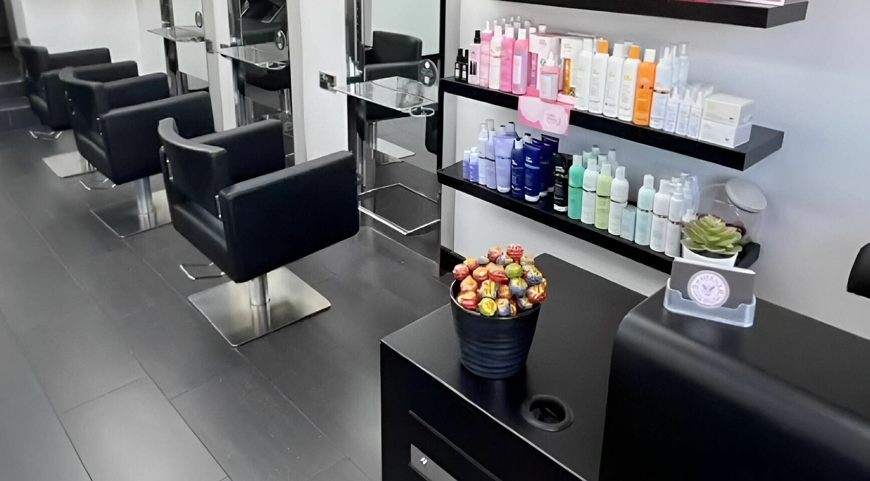 Stylish black chairs and shelves of products at Maverick Hair Studio, Angmering, England, GB.