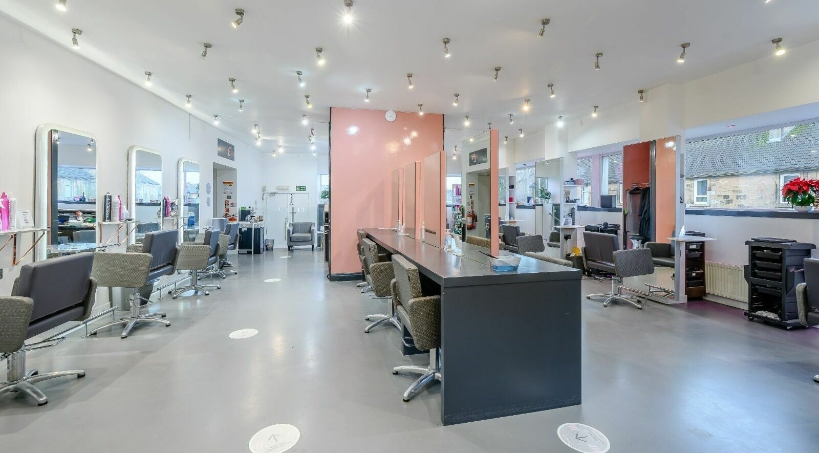 Spacious, modern interior of NBR Hair and Beauty in Clarkston, Scotland, GB, showcasing stylish salon stations.