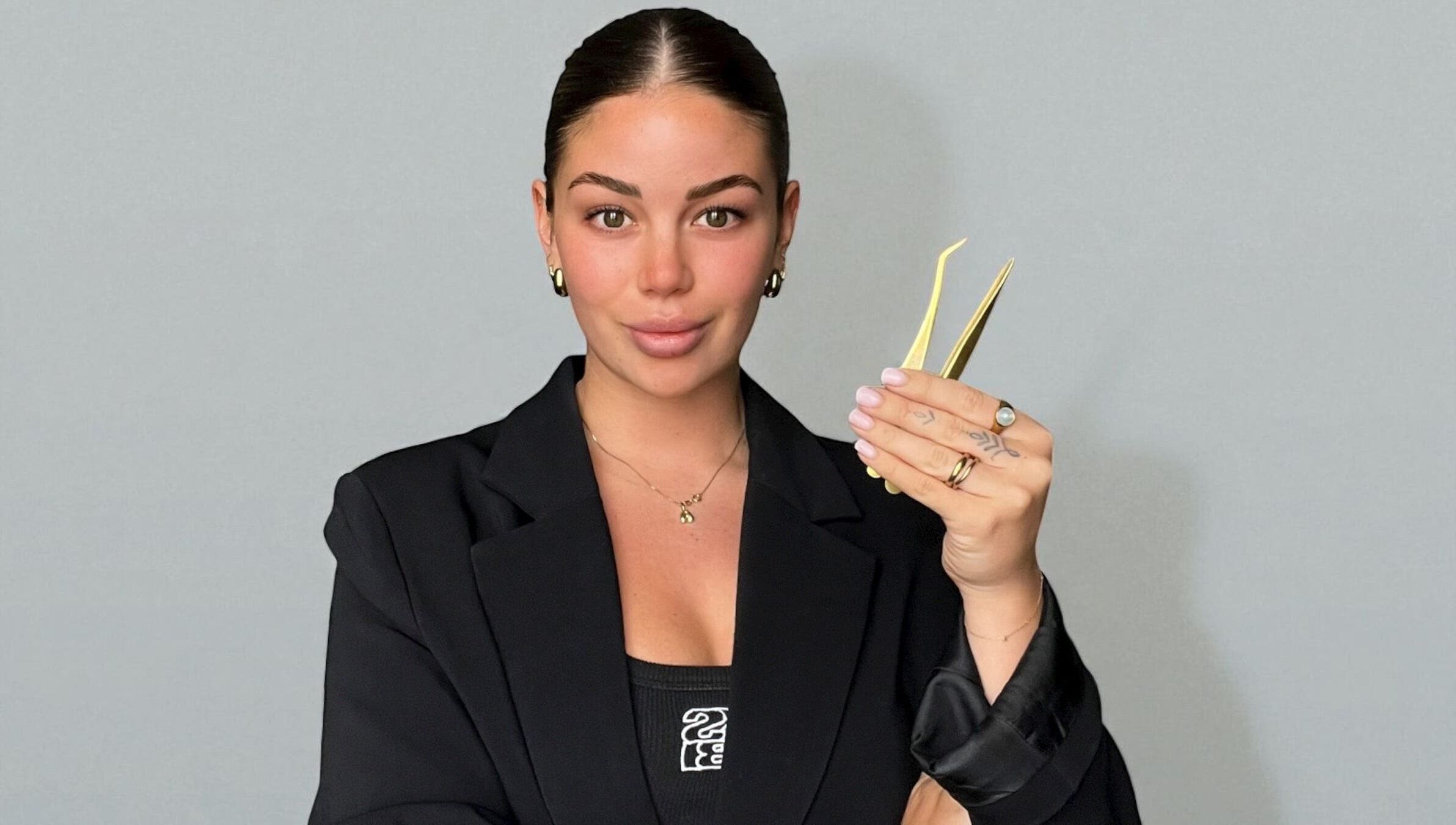 Professional at TAMED by Emily Taylor in St Leonards, NSW, AU holding precision tweezers, showcasing expertise.