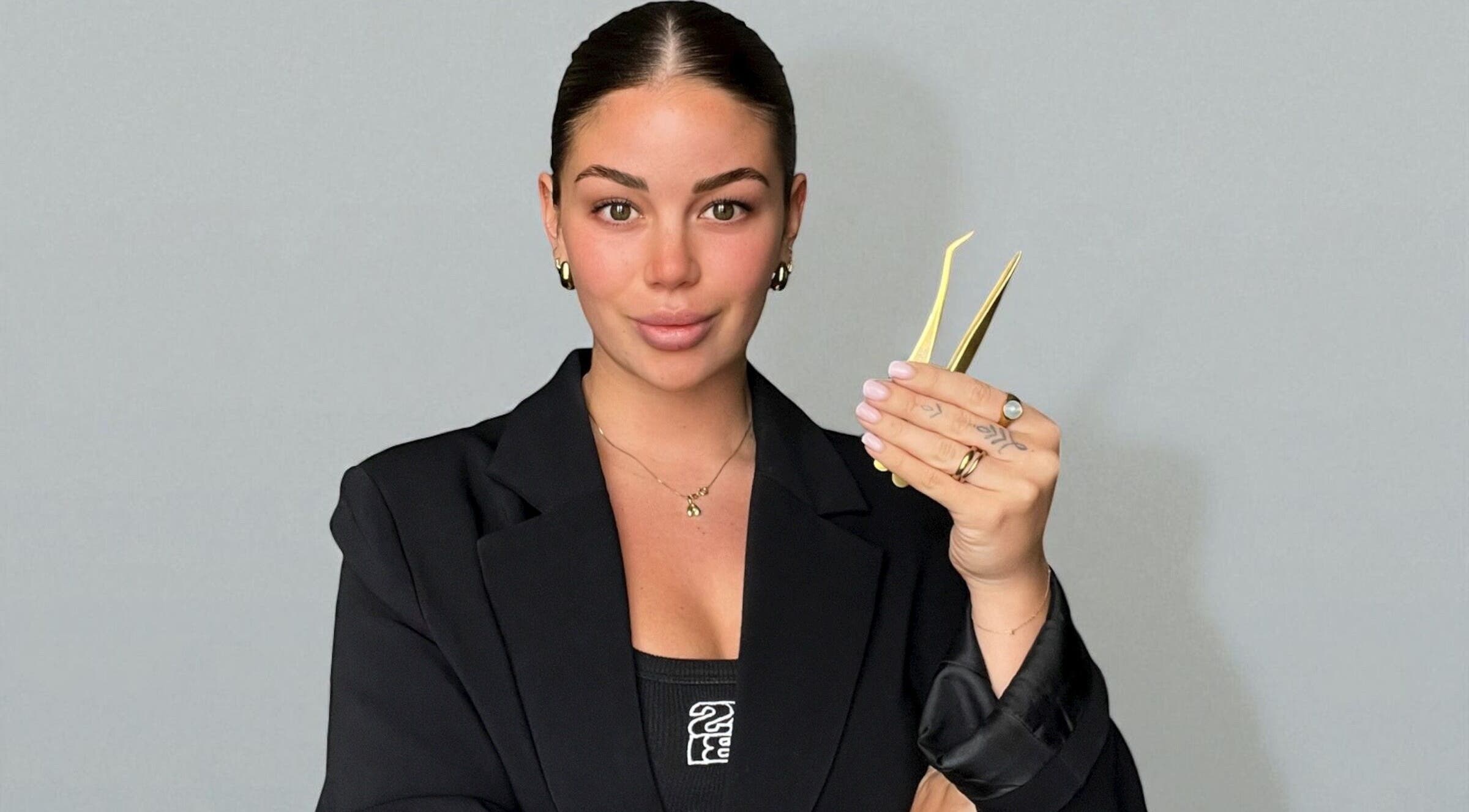 Professional at TAMED by Emily Taylor in St Leonards, NSW, AU holding precision tweezers, showcasing expertise.