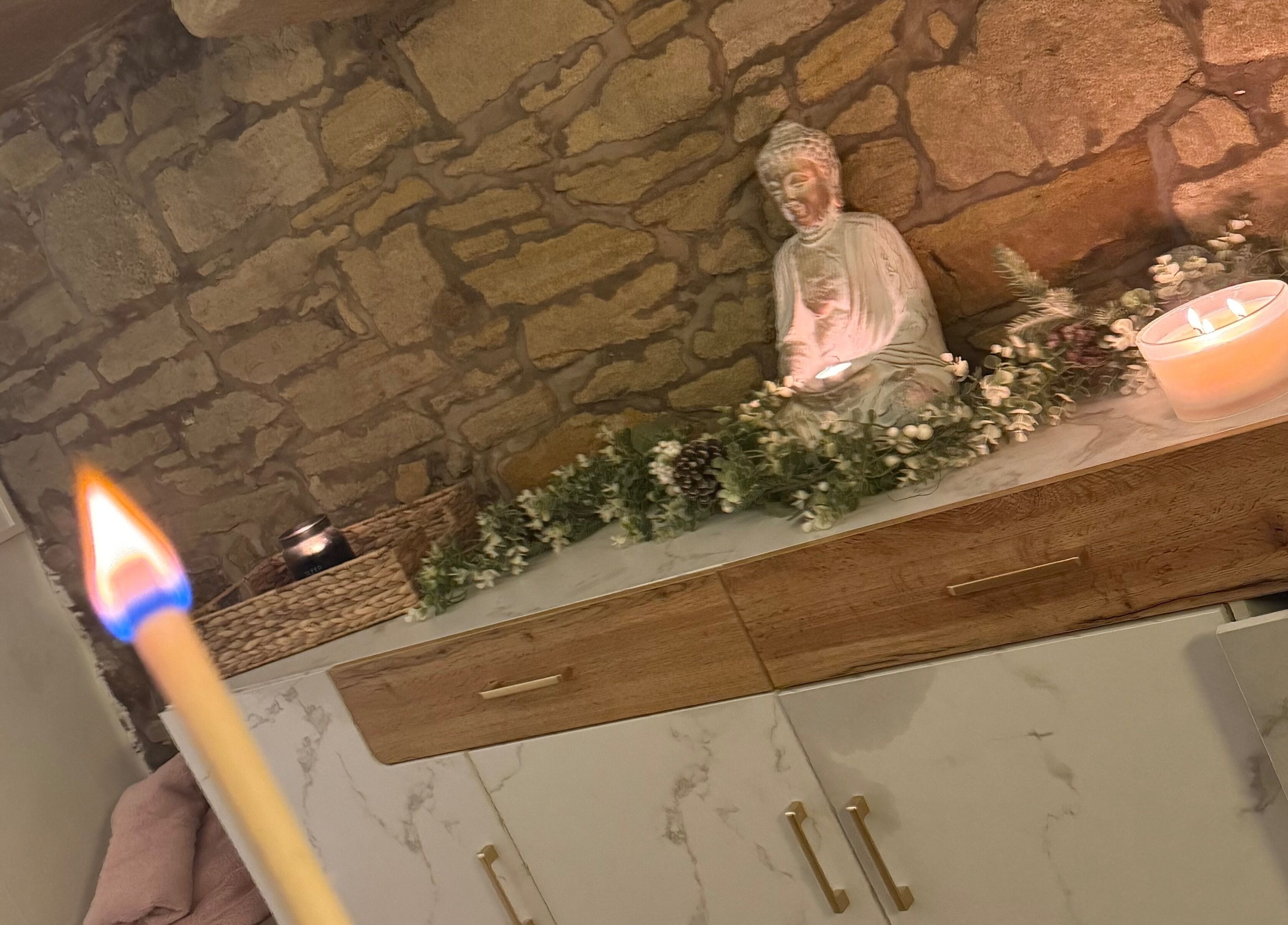 Cozy ambiance at My Treat in Ramsbottom, England, GB with candles and a Buddha statue on stone wall.