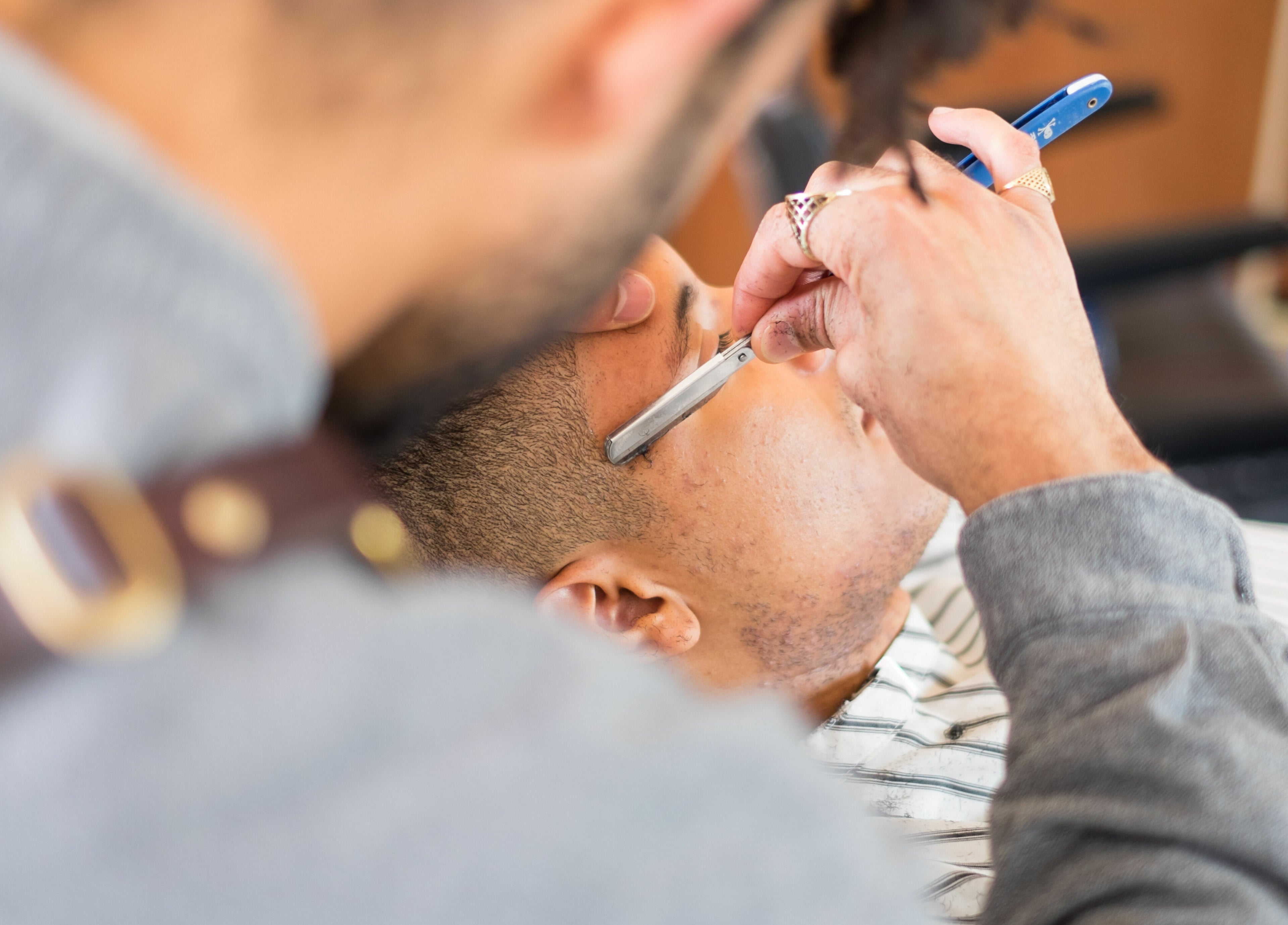 Barber providing a precise shave at ELP Barbershop, London, England, GB.